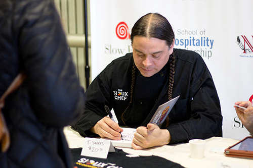 Sean Sherman signs copies of the cookbook he co-authoried at UW-Stout.