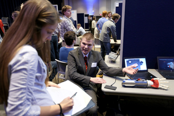 A student explains his robotic arm research project at the 2017 STEMM Expo.