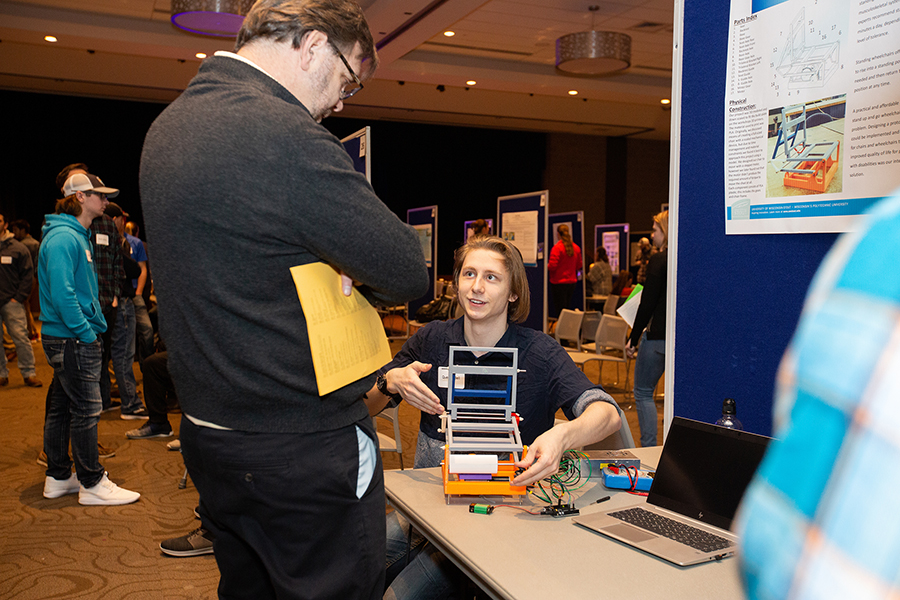 ​    ​A student explains research on a standup wheelchair to Chuck Bomar, dean of the College of Science, Technology, Engineering, Mathematics and Management.