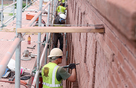 Workers take out mortar from a wall.