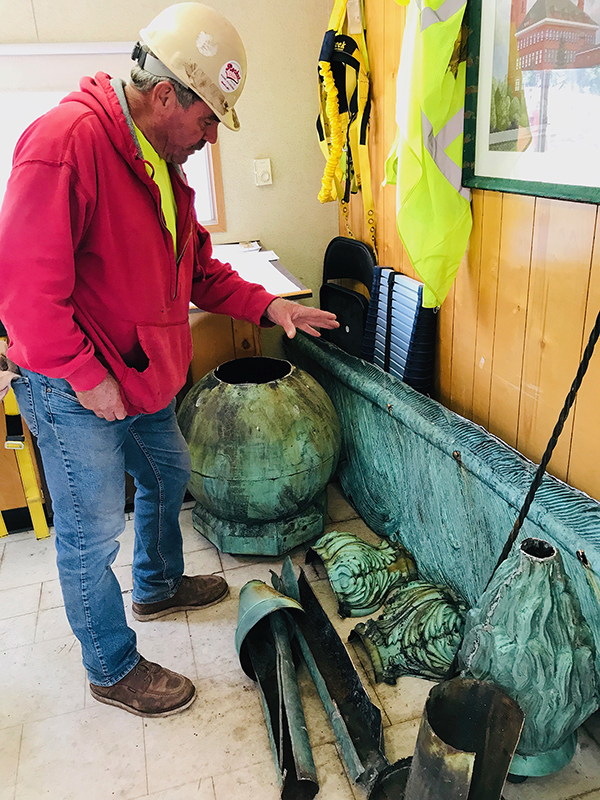 Joe Vaughan, Building Restoration Corp. foreman for the Bowman Hall project at UW-Stout, views the quill, torch and other parts, which will be restored or replaced.