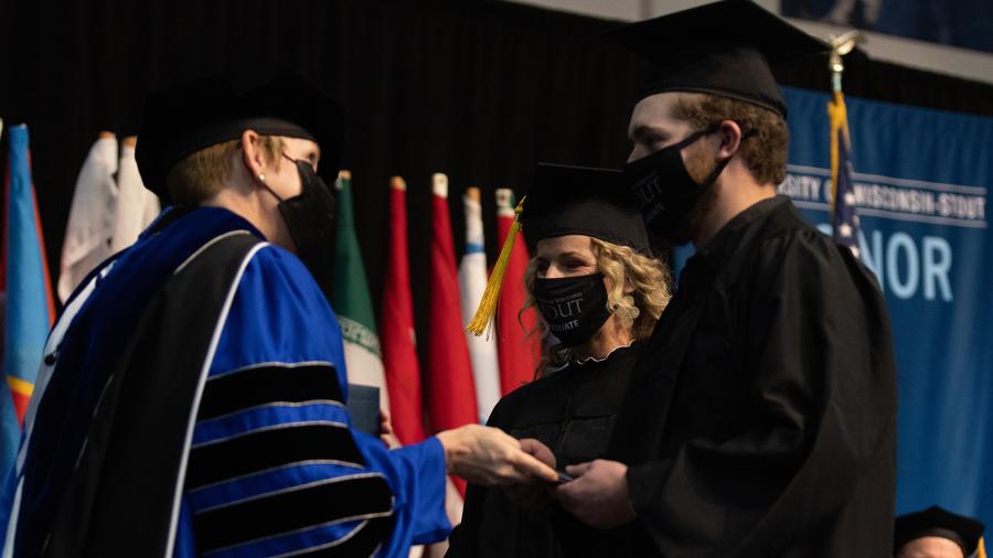 Chancellor Katherine Frank hands Mara and Jacob Harter their diplomas during a commencement ceremony.