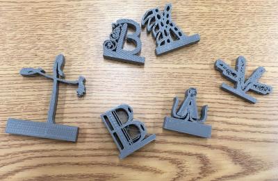 3D printed monograms, letters "T," "B," "K," "A," and "V."